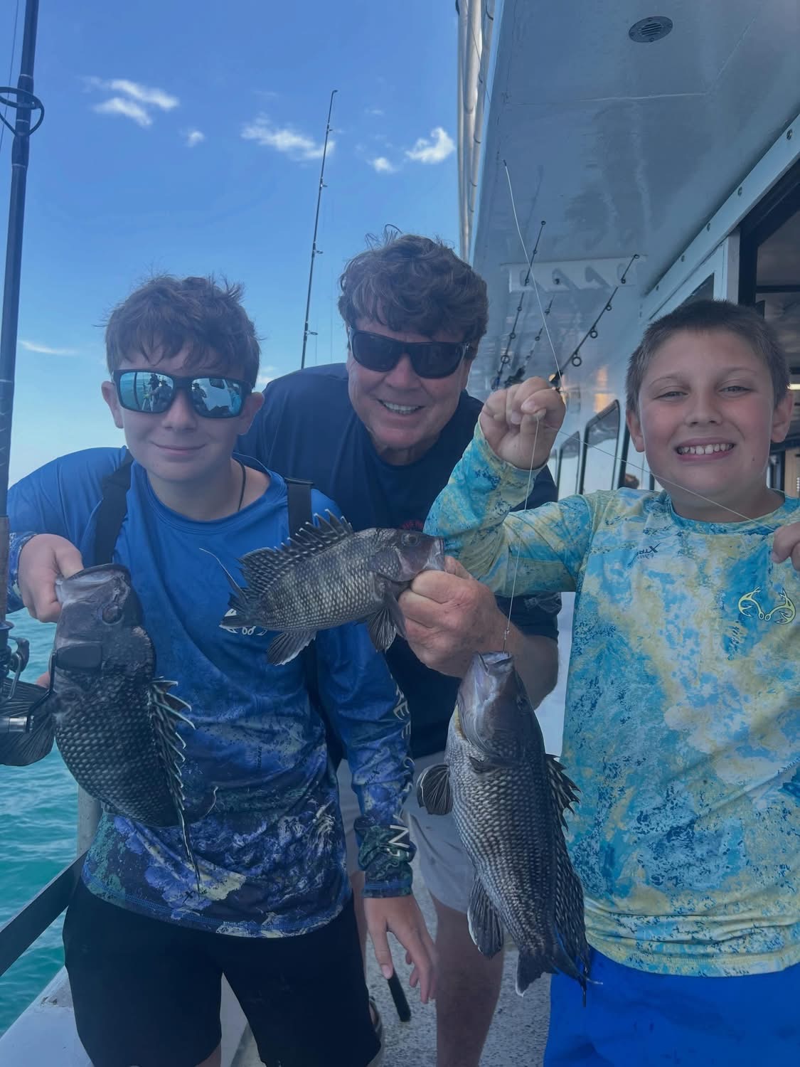 Two scouts and adult holding fish on charter boat off New Jersey