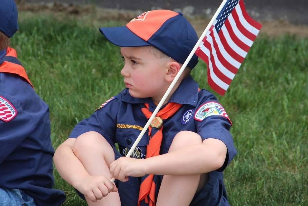 Young Scout holding American flag at ceremony